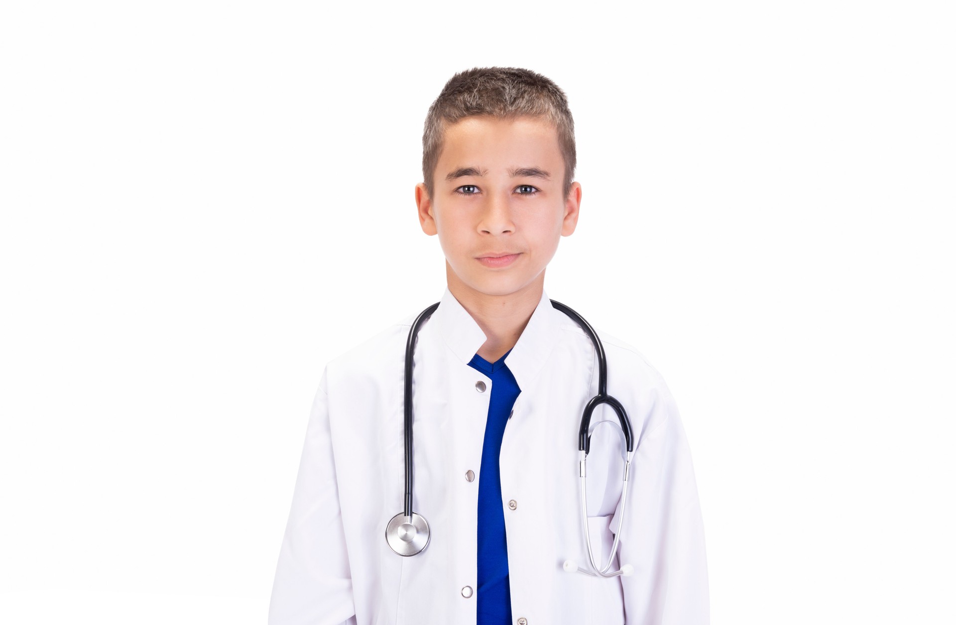 Portrait of cute teenage boy dressed as a doctor looking at camera with blank facial expression on white background